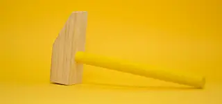 Wooden hammer painted in yellow in a yellow background